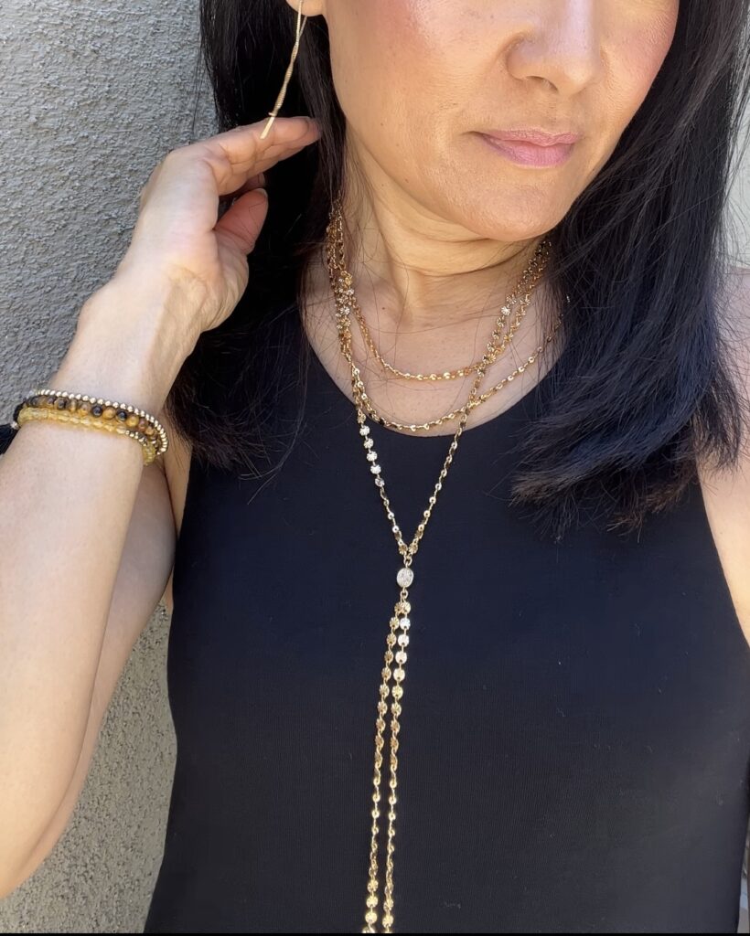 Close-up of Meesh wearing layered gold necklaces and a black sleeveless top — lifestyle content for jewelry or fashion.
