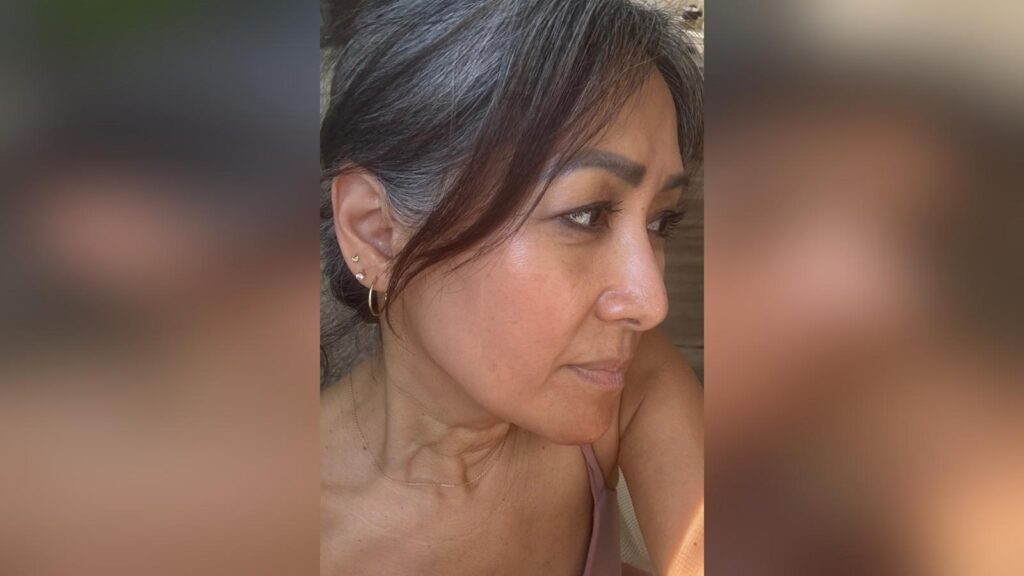 Close-up of a woman with natural gray hair looking to the side, reflecting confidence and beauty in midlife.