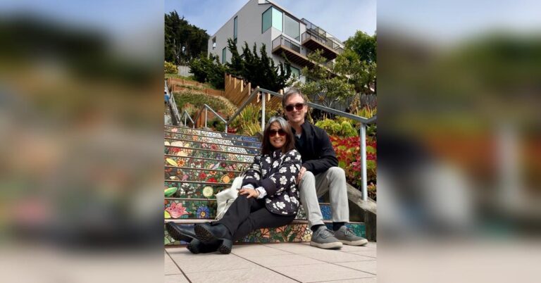 Smiling couple sitting on the colorful mosaic steps in San Francisco, reflecting a joyful midlife travel moment.